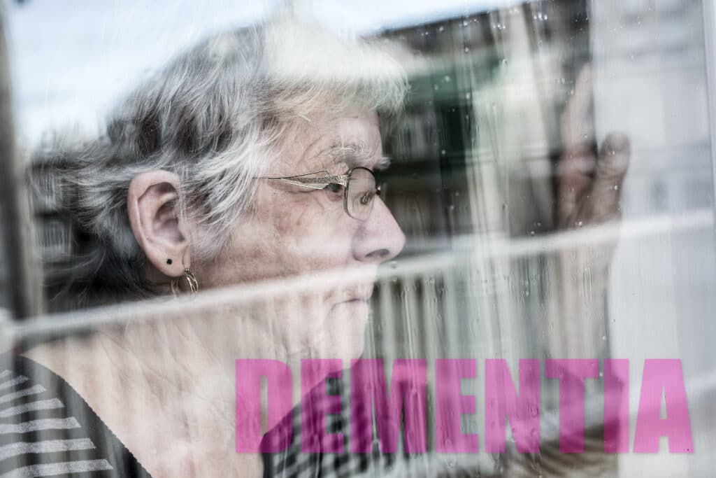 An older lady staring out the window and dementia written on the bottom