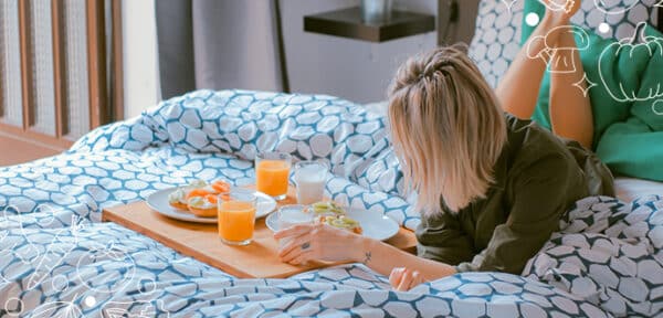 a women on a bed with tray of food and orange juice