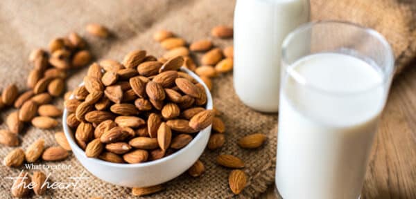 Almonds in a bowl next to a glass of milk