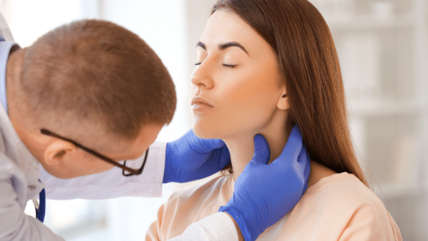 a doctor feeling a female patient thyroid